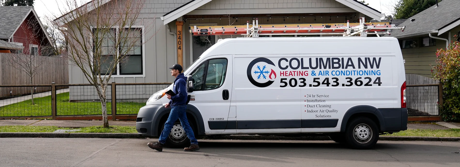 HVAC service professional in front of the Columbia NW van on an overcast afternoon